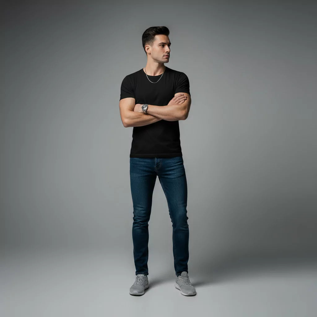Man wearing a black t-shirt, blue jeans, and gray sneakers on a gray background