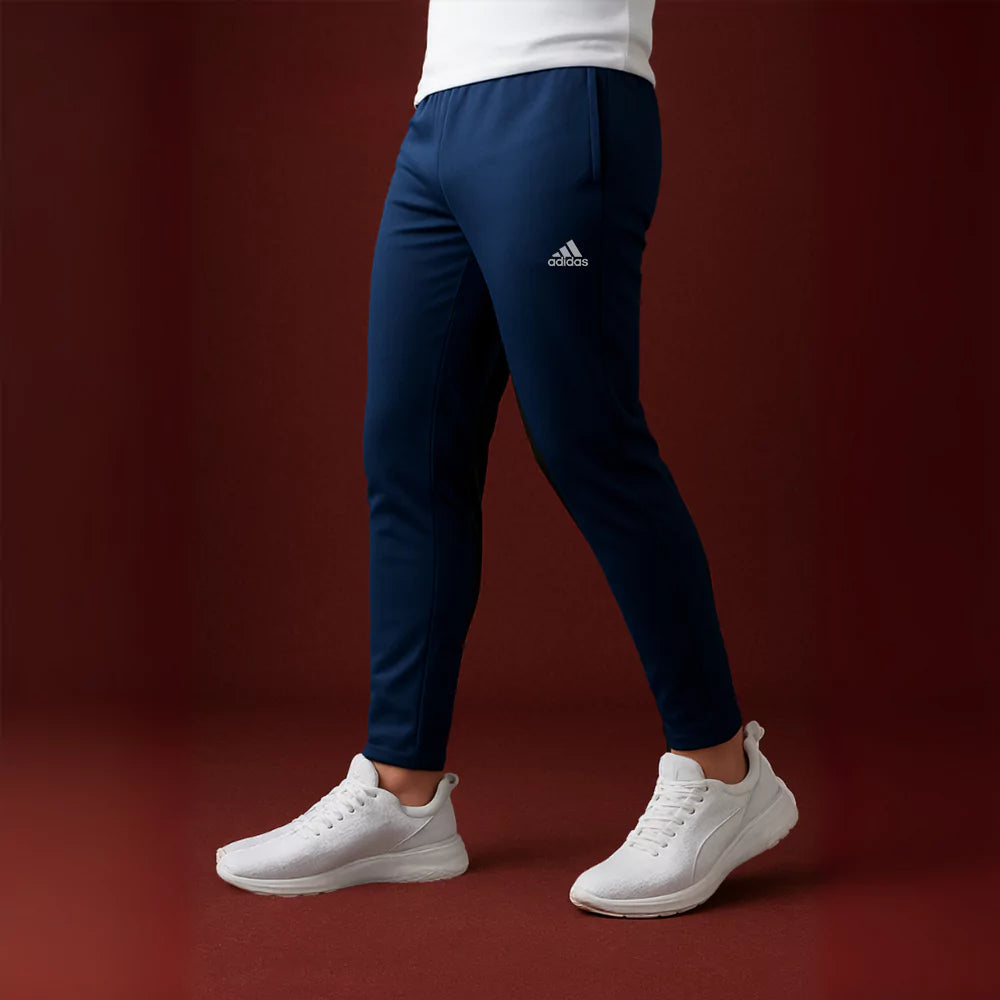 Person wearing navy Stride pants and white sneakers on a red background