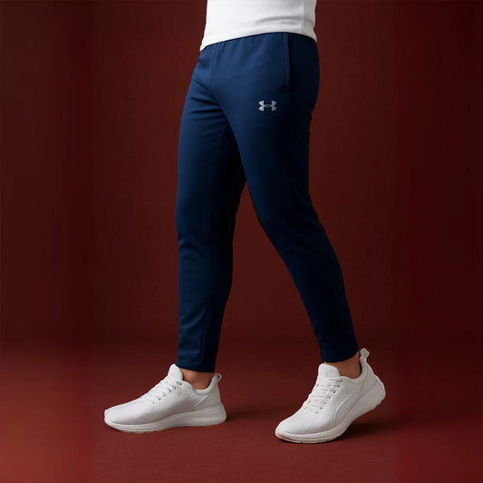 Person wearing navy Armour pants and white sneakers on a brown background