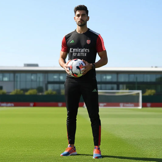 Person holding a soccer ball on a sports field with Emirates branding