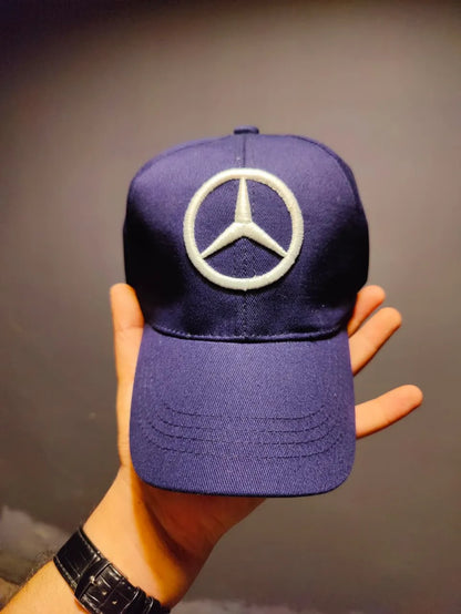 Purple cap with Mercedes-Benz logo held by a hand against a neutral background