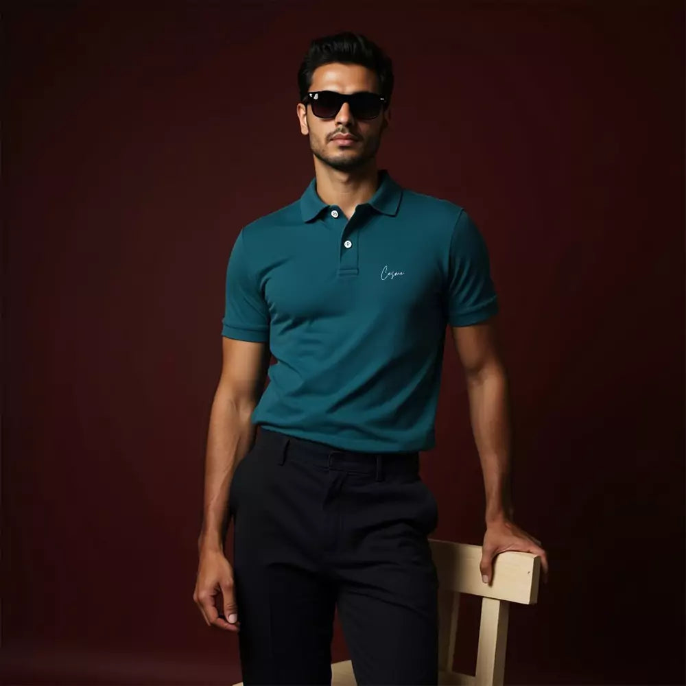 Man wearing a teal polo shirt and sunglasses against a dark background