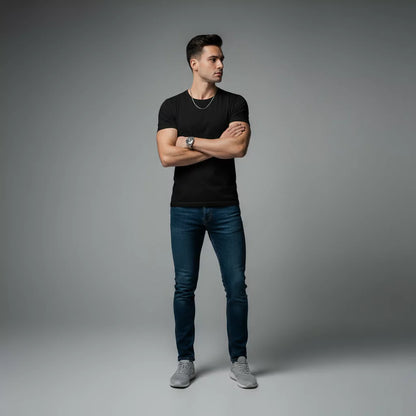 Man wearing a black t-shirt, blue jeans, and gray sneakers on a gray background