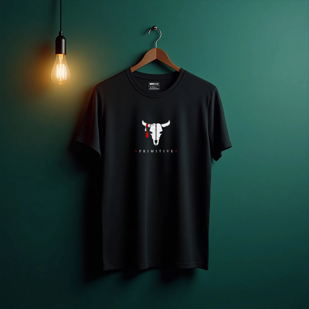 Black t-shirt with a bull skull design on a hanger against a green wall.